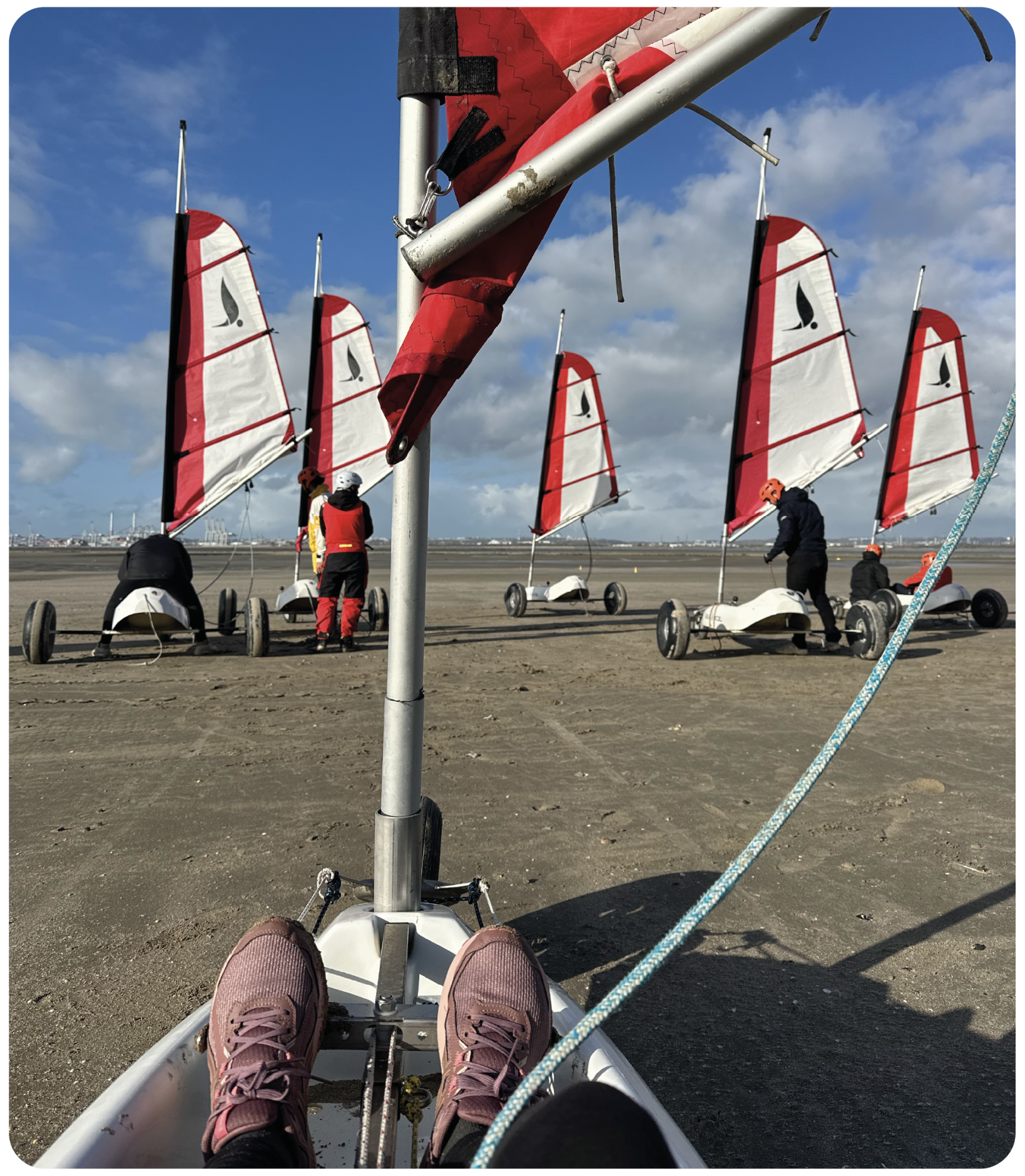 Préparation d’une séance de char à voile à Honfleur : un participant prend place dans son char avant le départ, avec les autres chars alignés sur la plage.